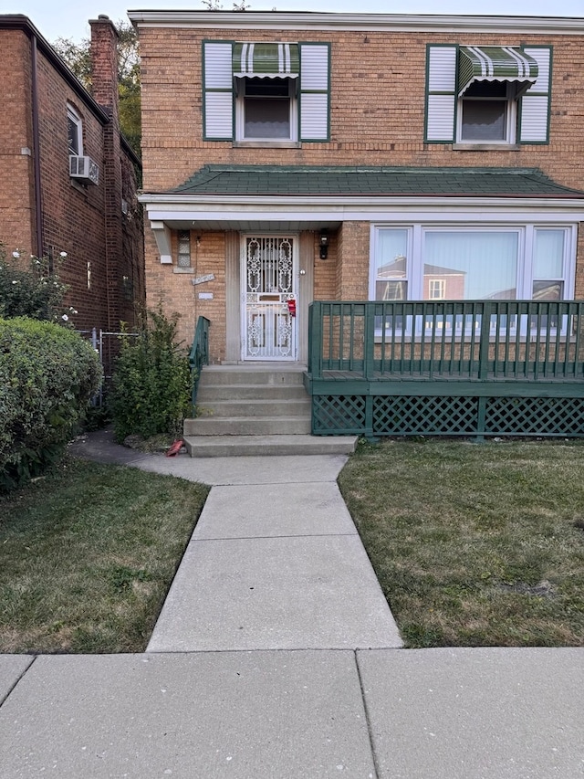 doorway to property with a deck and a lawn