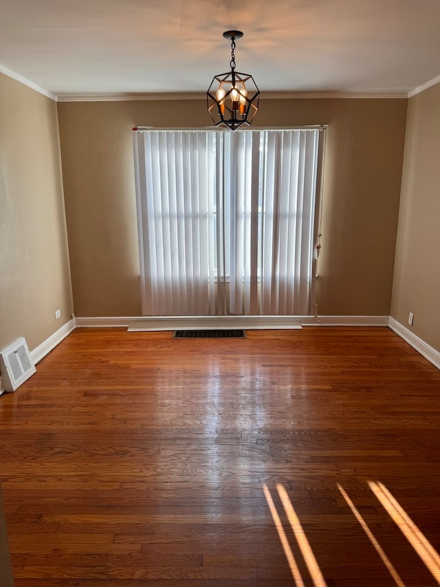 spare room featuring a notable chandelier, crown molding, and dark hardwood / wood-style flooring