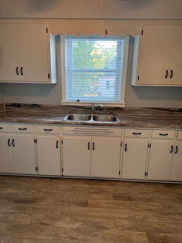 kitchen with white cabinets, light hardwood / wood-style floors, and sink