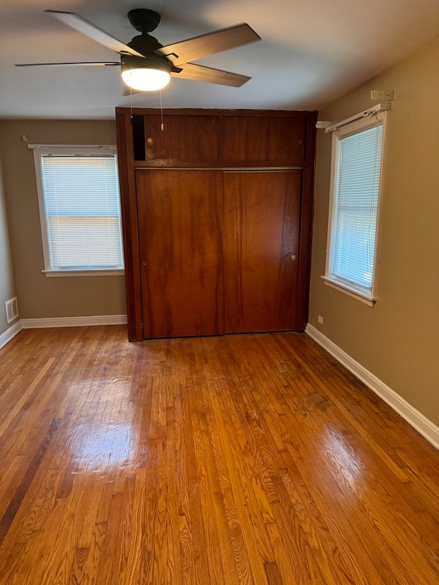 unfurnished bedroom with light hardwood / wood-style floors, multiple windows, and ceiling fan