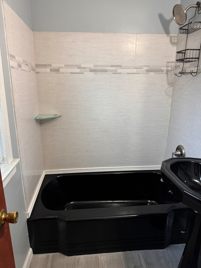 bathroom with hardwood / wood-style flooring and a bathtub