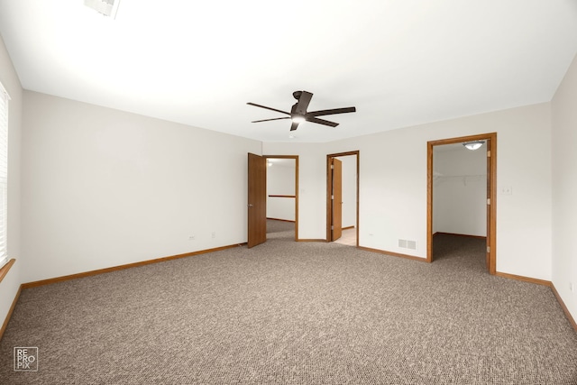 unfurnished bedroom with a spacious closet, a closet, ceiling fan, and carpet flooring