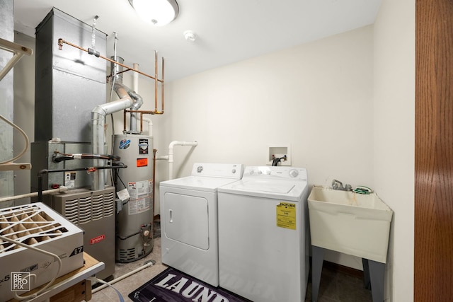 clothes washing area with water heater, sink, and washing machine and dryer