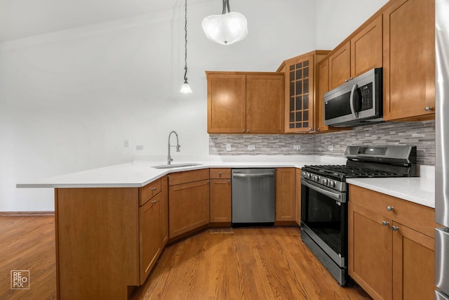 kitchen featuring appliances with stainless steel finishes, kitchen peninsula, sink, and pendant lighting