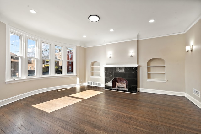 unfurnished living room featuring a tile fireplace, ornamental molding, dark hardwood / wood-style flooring, and built in features