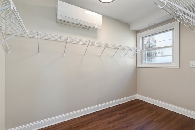 walk in closet featuring a wall unit AC and dark hardwood / wood-style flooring