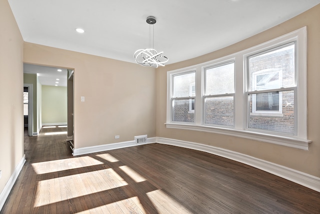 spare room featuring dark hardwood / wood-style floors and a notable chandelier