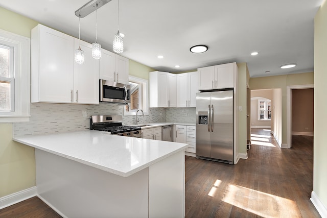 kitchen with white cabinets, sink, appliances with stainless steel finishes, and kitchen peninsula