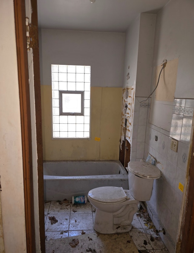 bathroom featuring tile walls, tile patterned floors, a bathtub, and toilet