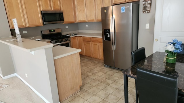 kitchen with kitchen peninsula, a breakfast bar, stainless steel appliances, and light tile patterned flooring