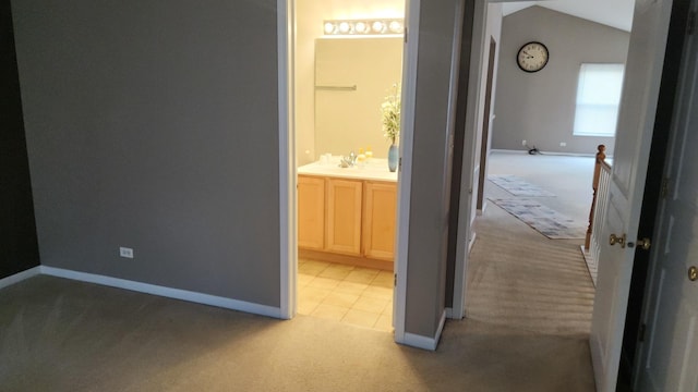 hallway with light carpet, vaulted ceiling, and sink