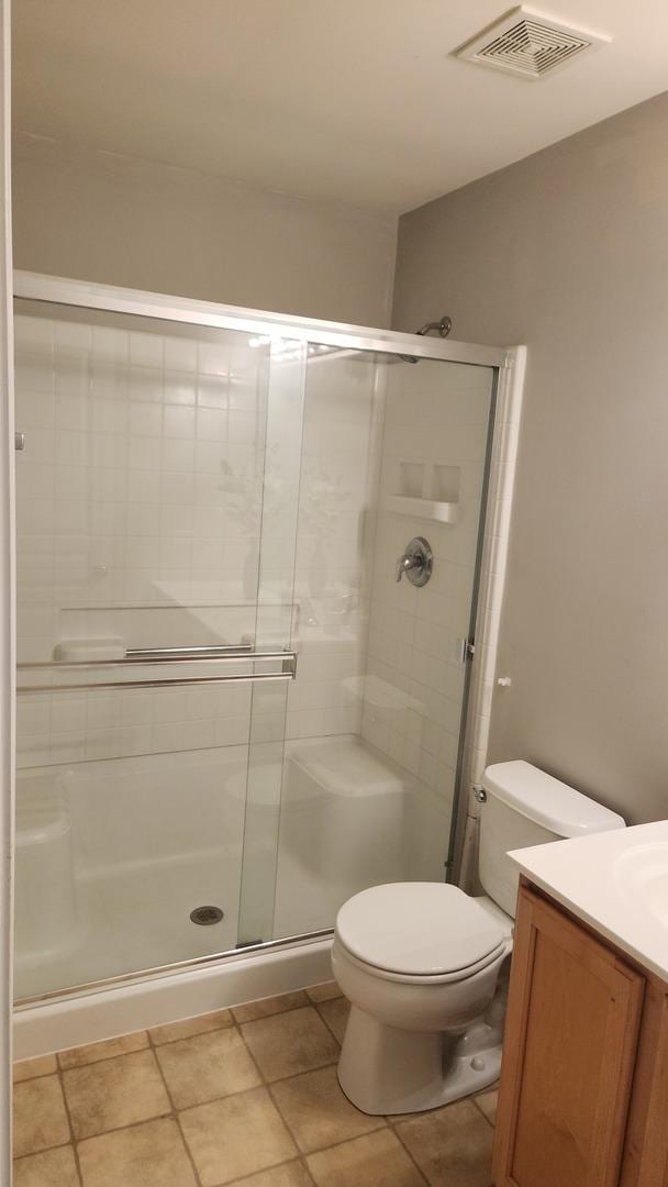 bathroom with tile patterned flooring, vanity, toilet, and a shower with shower door