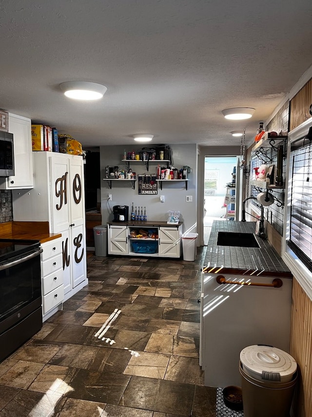 kitchen with stainless steel appliances, white cabinets, and a textured ceiling