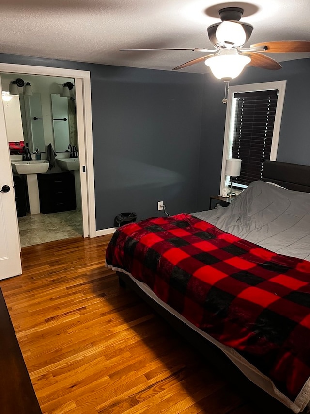 bedroom with a textured ceiling, hardwood / wood-style floors, ceiling fan, and sink