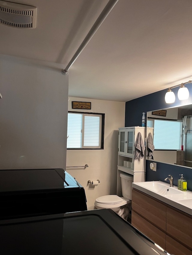 bathroom with vanity, toilet, and a healthy amount of sunlight