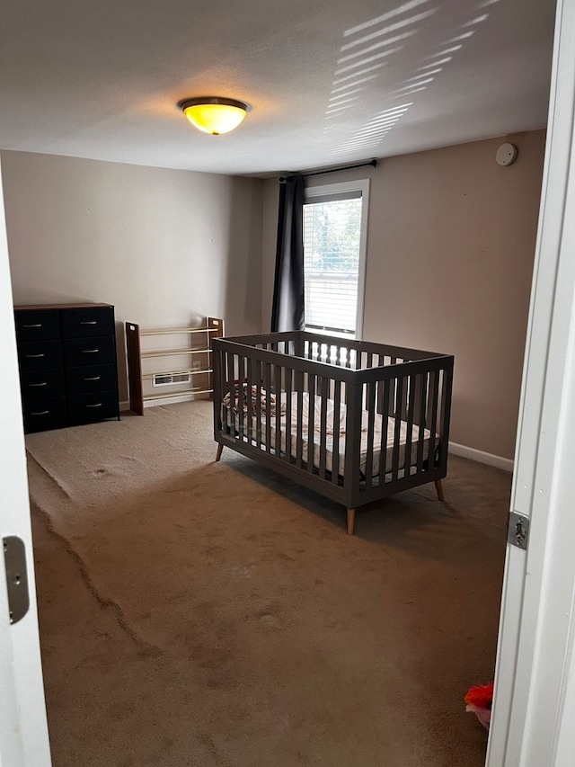 bedroom with a crib and dark colored carpet