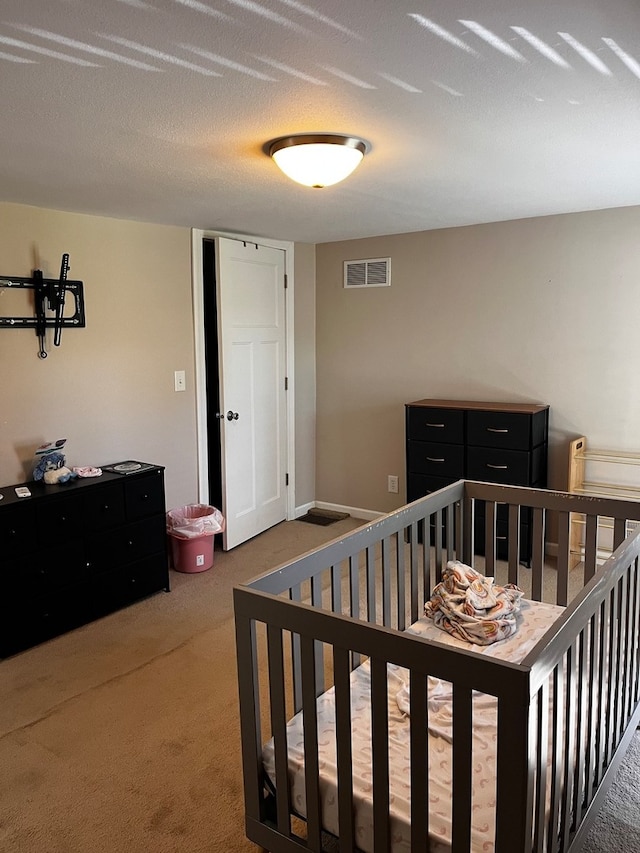 carpeted bedroom with a nursery area and a textured ceiling