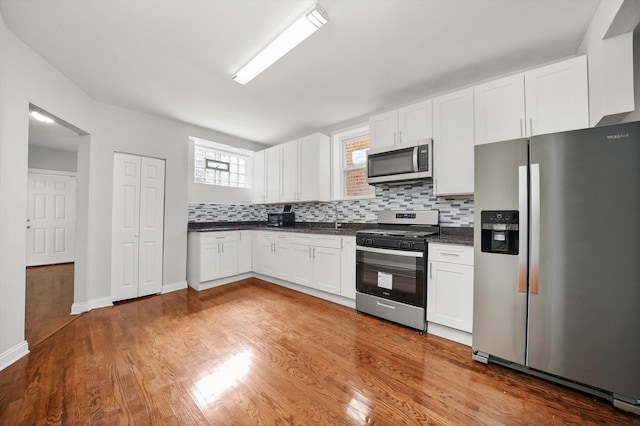 kitchen featuring stainless steel appliances, sink, tasteful backsplash, hardwood / wood-style floors, and white cabinets