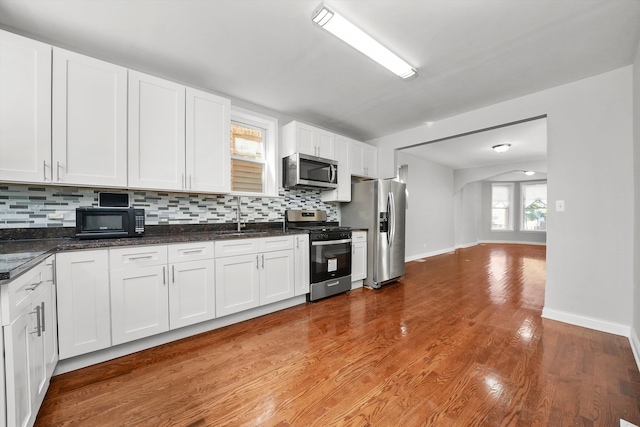 kitchen featuring white cabinets, appliances with stainless steel finishes, tasteful backsplash, and light hardwood / wood-style flooring