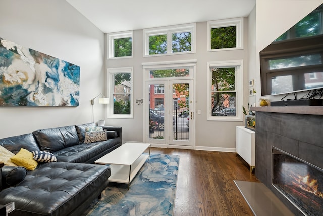 living room featuring french doors, dark hardwood / wood-style floors, high vaulted ceiling, and a tile fireplace