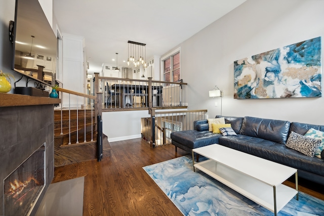 living room featuring a chandelier, a tile fireplace, and dark hardwood / wood-style floors