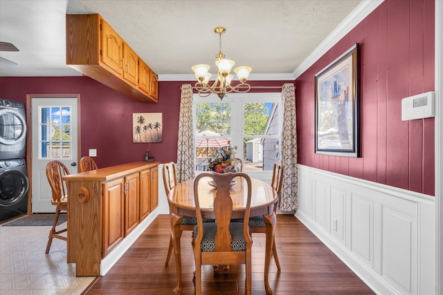 dining area featuring stacked washing maching and dryer, a healthy amount of sunlight, wood-type flooring, and ornamental molding