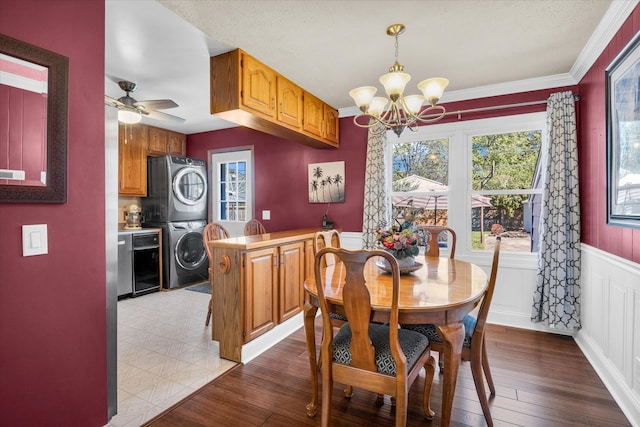 dining area featuring ornamental molding, stacked washing maching and dryer, ceiling fan with notable chandelier, and light wood-type flooring