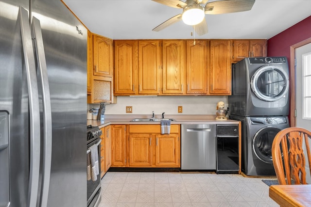 kitchen with sink, appliances with stainless steel finishes, ceiling fan, and stacked washing maching and dryer