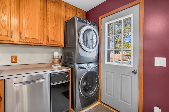 laundry area featuring cabinets and stacked washing maching and dryer