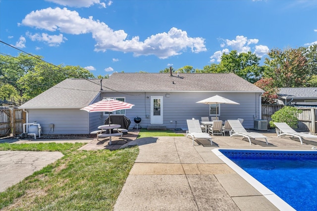 rear view of house featuring a patio, a fenced in pool, and central AC unit