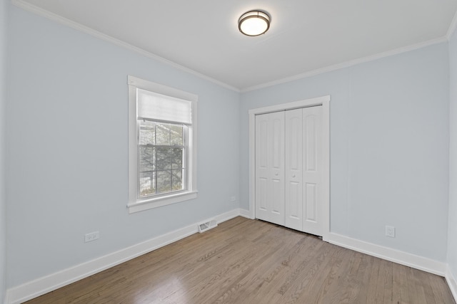 unfurnished bedroom featuring light wood-type flooring, ornamental molding, and a closet