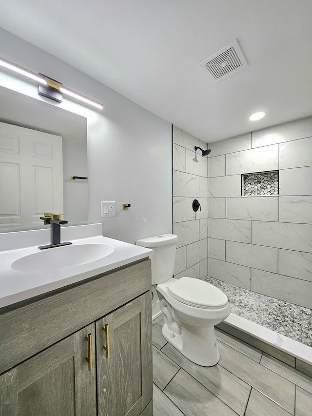 bathroom featuring vanity, toilet, and tiled shower