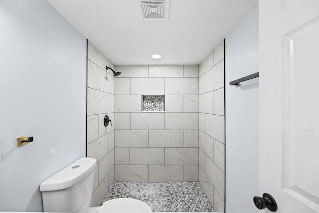 bathroom featuring toilet and a tile shower