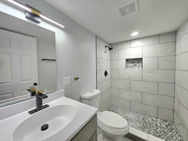 bathroom featuring vanity, toilet, and a tile shower