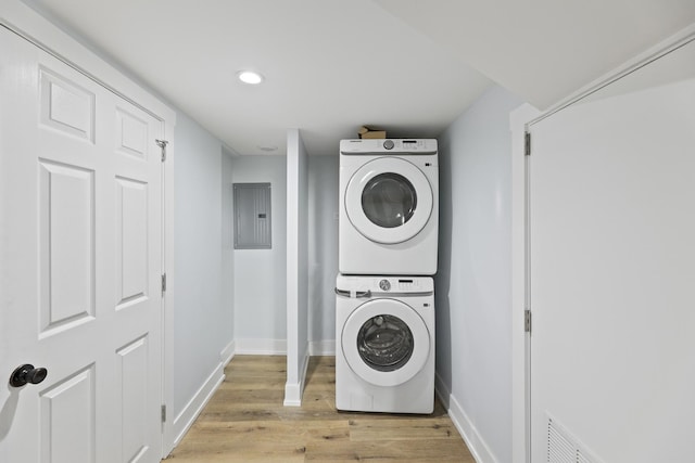 clothes washing area featuring light wood-type flooring, electric panel, and stacked washer / drying machine