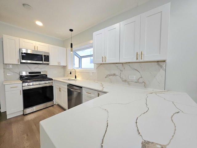 kitchen with white cabinetry, sink, stainless steel appliances, and decorative light fixtures