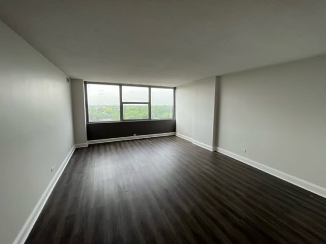 spare room with dark wood-type flooring and baseboards