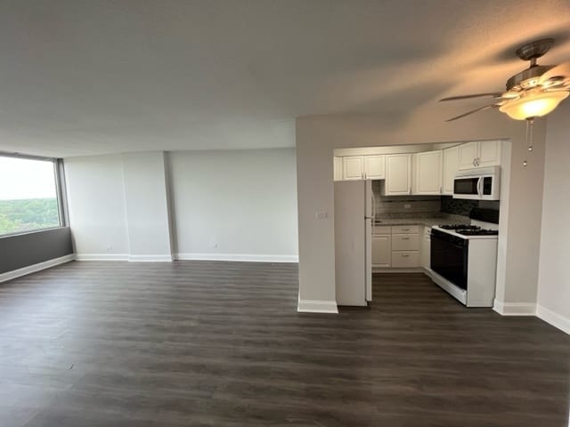kitchen with white appliances, dark wood-style flooring, ceiling fan, and baseboards