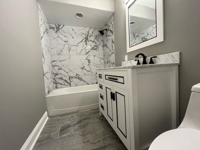 bathroom with vanity, marble finish floor, bathing tub / shower combination, toilet, and baseboards