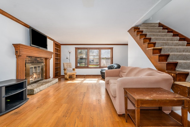 living room featuring built in shelves, light wood-type flooring, and ornamental molding