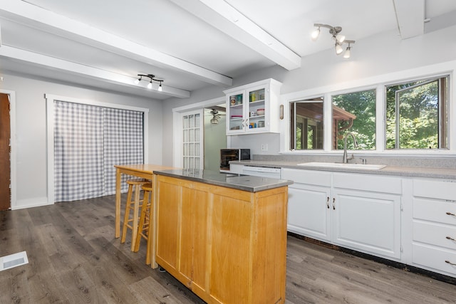 kitchen featuring a center island, white cabinets, sink, dark hardwood / wood-style floors, and a kitchen bar