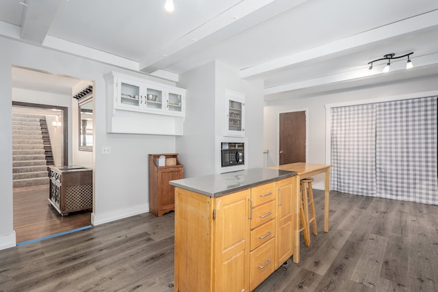 kitchen with a kitchen bar, light brown cabinetry, a center island, and dark hardwood / wood-style floors