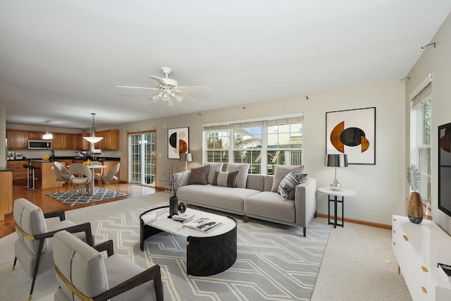 living room with ceiling fan, a healthy amount of sunlight, and light carpet