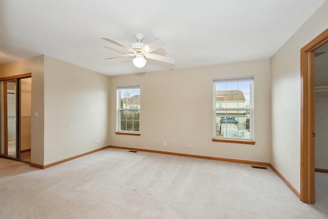 unfurnished bedroom with multiple windows, light colored carpet, and ceiling fan