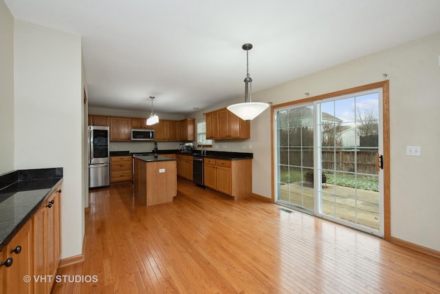 kitchen featuring a center island, light wood-type flooring, hanging light fixtures, and appliances with stainless steel finishes