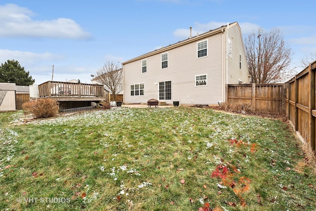 back of property with a lawn, a fire pit, and a deck