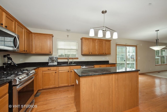 kitchen featuring sink, hanging light fixtures, light hardwood / wood-style floors, a kitchen island, and stainless steel appliances