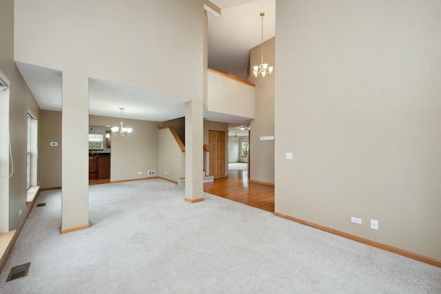 unfurnished living room with a notable chandelier, carpet floors, and a towering ceiling