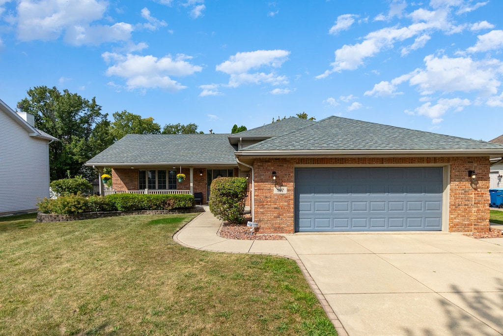 ranch-style home featuring a garage, covered porch, and a front yard