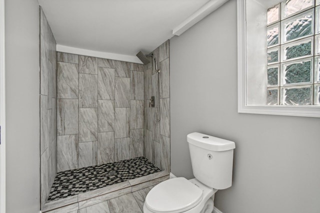 bathroom featuring tiled shower and toilet